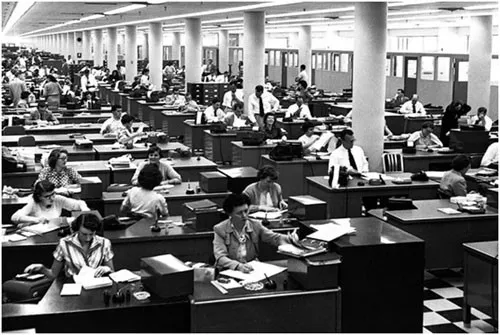 A black and white photograph of a vast open plan clerical office packed with desks